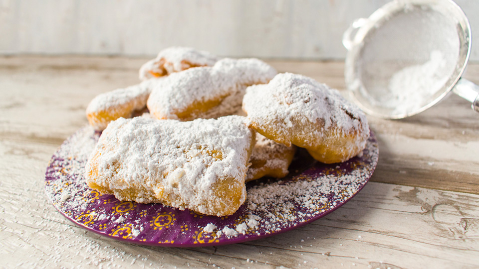 Delicious beignets donuts with jam on a table