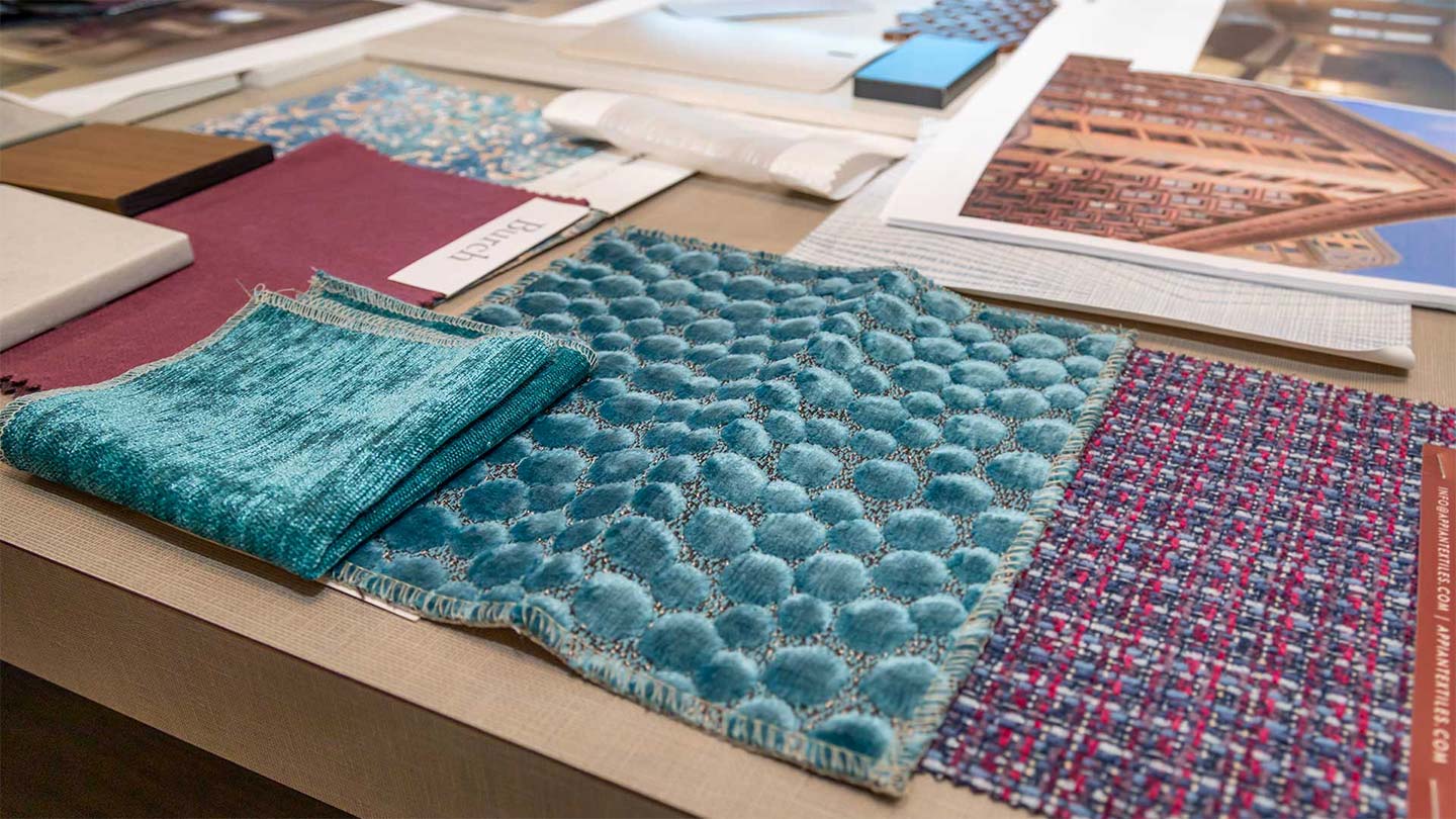 Various fabrics and reference images laid out on a table